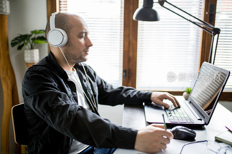 男人在家工作，坐在笔记本电脑前通过互联网开会