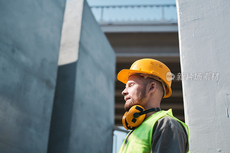 建筑工人戴着安全帽，站在未完工建筑的屋顶上拷贝空间