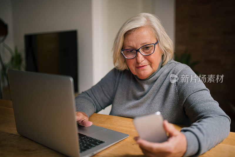 金发老女人用手提电脑和手机。