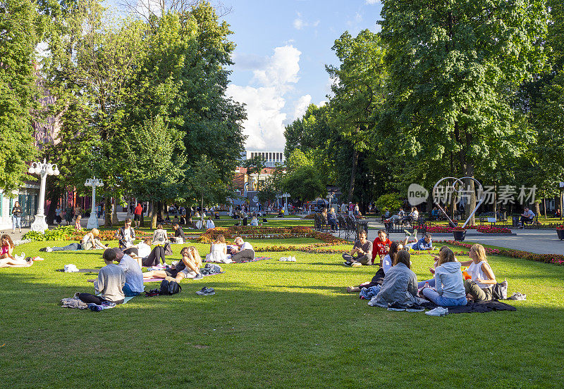在俄罗斯温暖的阳光明媚的日子里，人们正在莫斯科冬宫花园或冬宫公园休息。