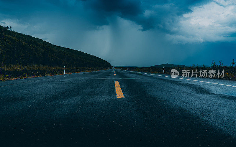 雨后，高速公路与山和乌云在黑暗的背景。