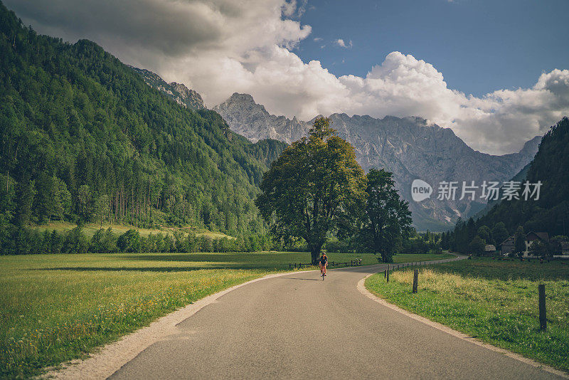 女公路摩托车手沿着阳光明媚的乡村公路行驶