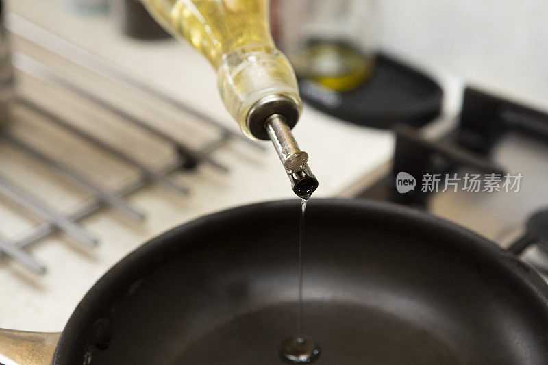 一个家庭厨房里橄榄油被倒进煎锅的特写镜头