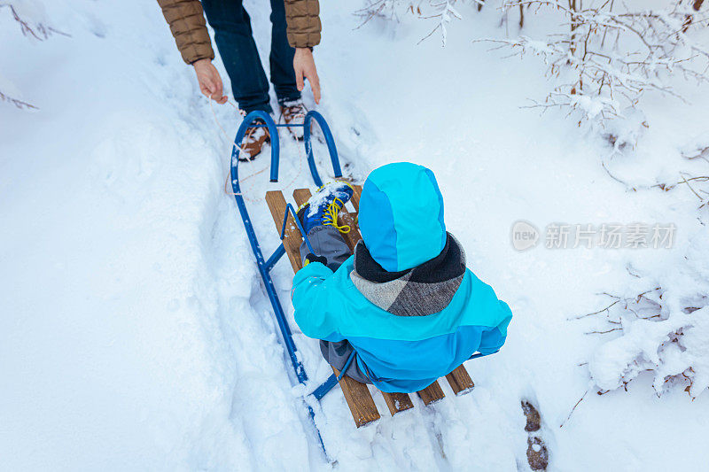 寒假里，男孩和家人一起玩雪橇玩得很开心