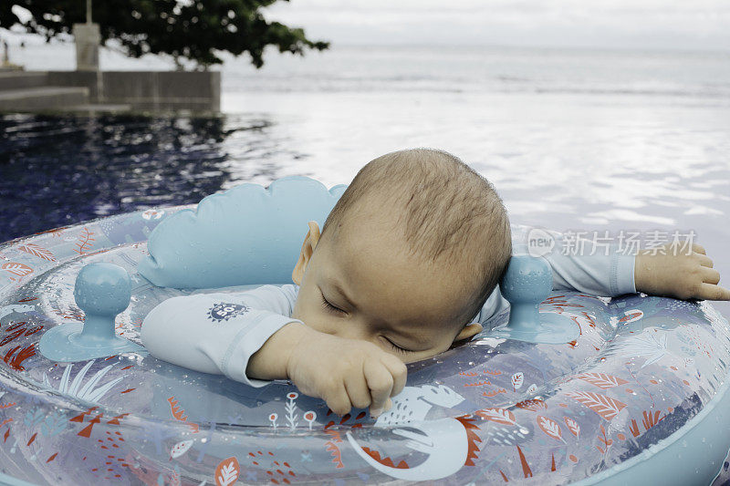 亚洲婴儿睡在游泳池的浮标上