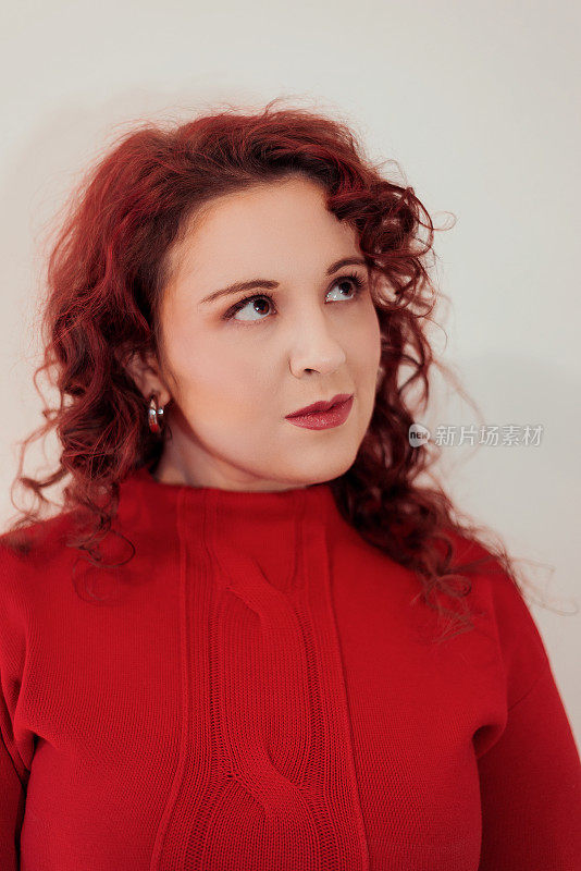 年轻和美丽的红头发女人肖像穿着红色套头衫和向上看