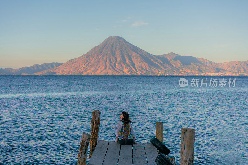 日落时分，坐在危地马拉阿提特兰湖码头上的女人