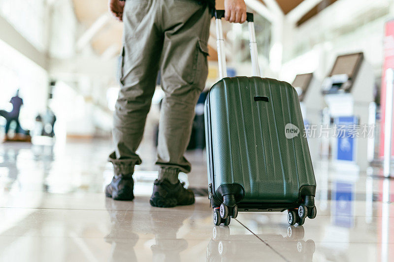 在机场带着轮式行李箱的男子