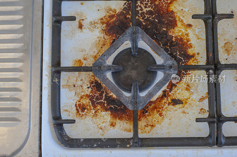 用剩菜弄脏炉子。不干净的燃气厨房灶台上有油腻的斑点，旧的脂肪渍，油炸的斑点和油飞溅