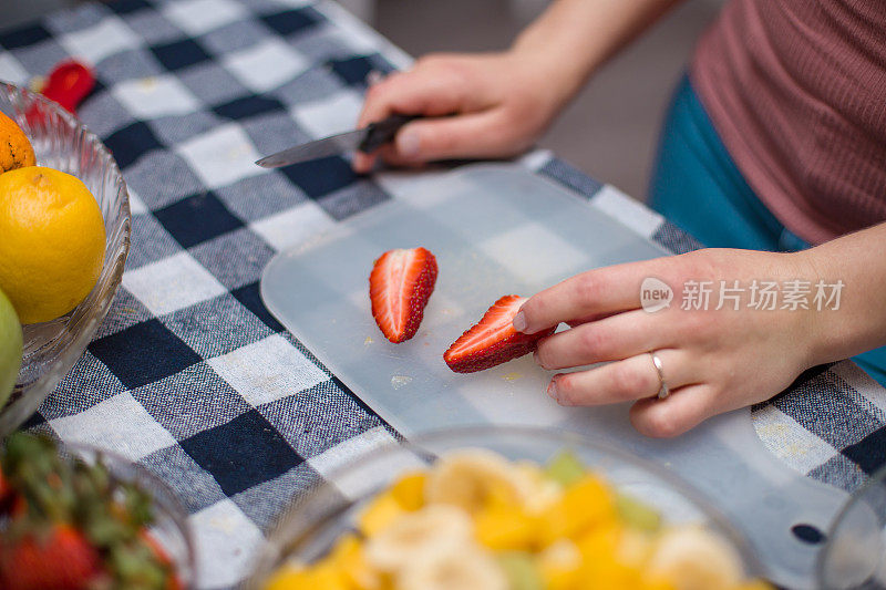 小女孩在做新鲜水果沙拉，切草莓