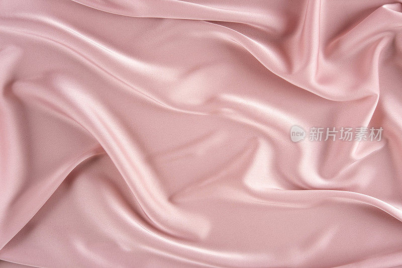 粉色丝绸背景。波浪褶皱粉红色丝绸质地缎面材料。面料的质地。粉红色的背景布。文本。