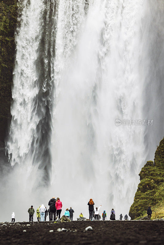 站在斯科加福斯瀑布下的游客——近距离垂直拍摄