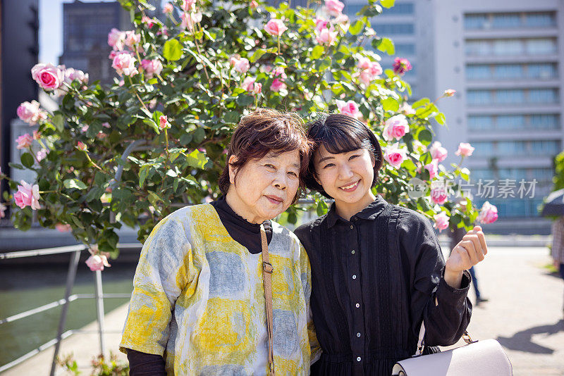年轻女子和她的祖母站在城市公园里的肖像