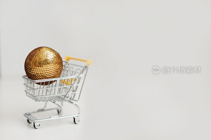 白色背景圣诞球的小购物车。网上购物，超市，折扣促销和黑色星期五概念的创意。新年和圣诞节大甩卖和购物