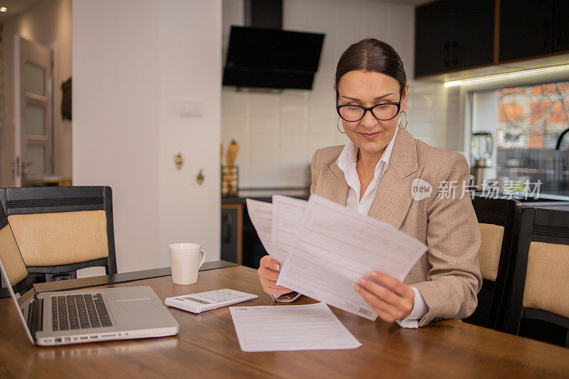 成熟的女人在计算账单和家庭财务时使用计算器