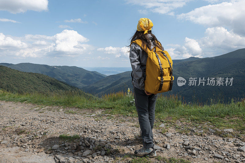 在一个阳光明媚的日子里在树林里徒步旅行的女游客。