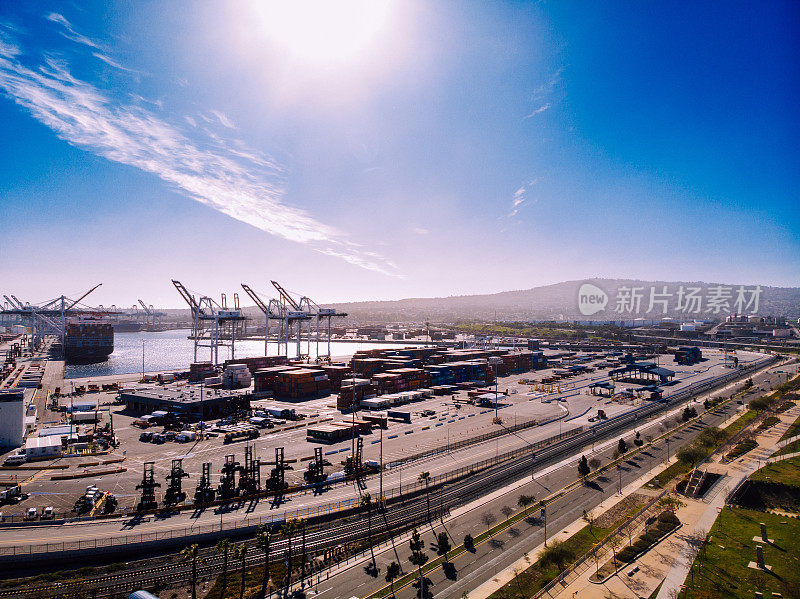 从空中俯瞰，熙熙攘攘的洛杉矶港口展现出一幅令人着迷的挂毯，整齐排列的集装箱，一个充满活力的贸易迷宫。起重机优雅地摇摆着，装卸货船，在广阔的天空下商业蓬勃发展。