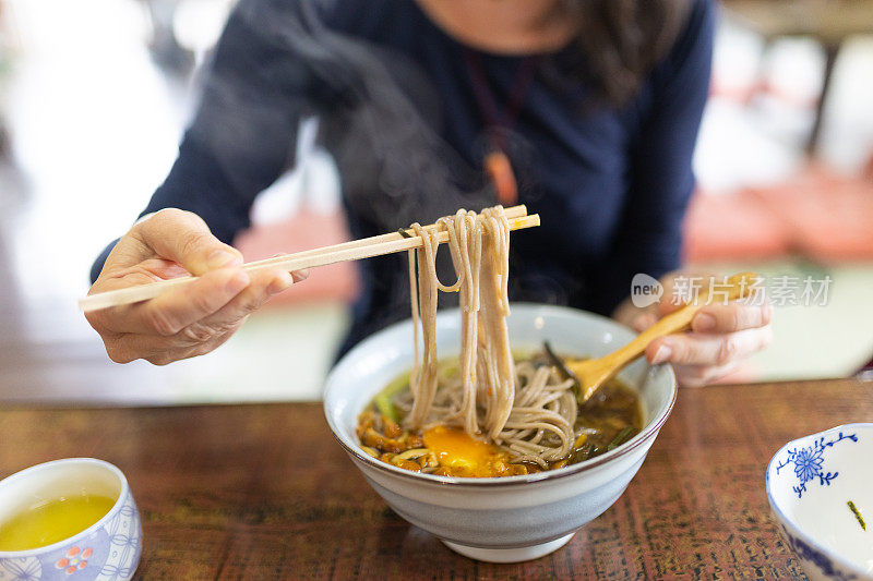 在日本，一名妇女正在享用蔬菜荞麦面