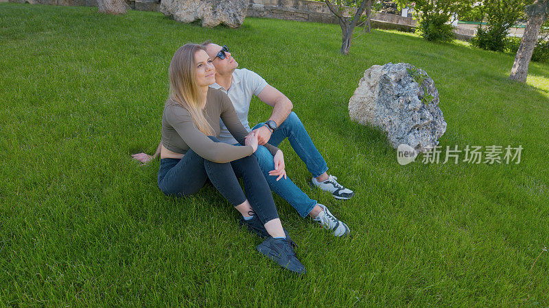 这对夫妇在绿草地上休息，享受着周围的自然环境