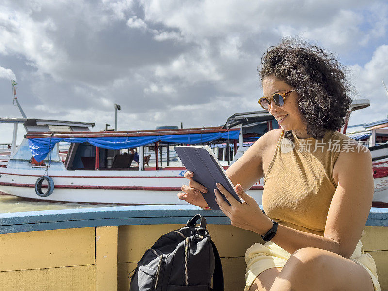 微笑的拉丁女人在船上使用平板电脑