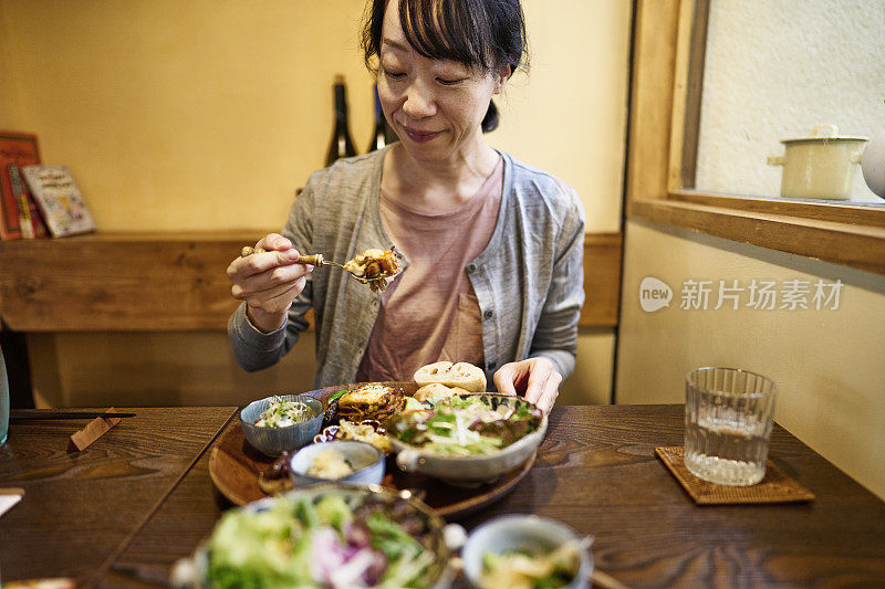 一位亚洲妇女在素食餐厅吃素食午餐。