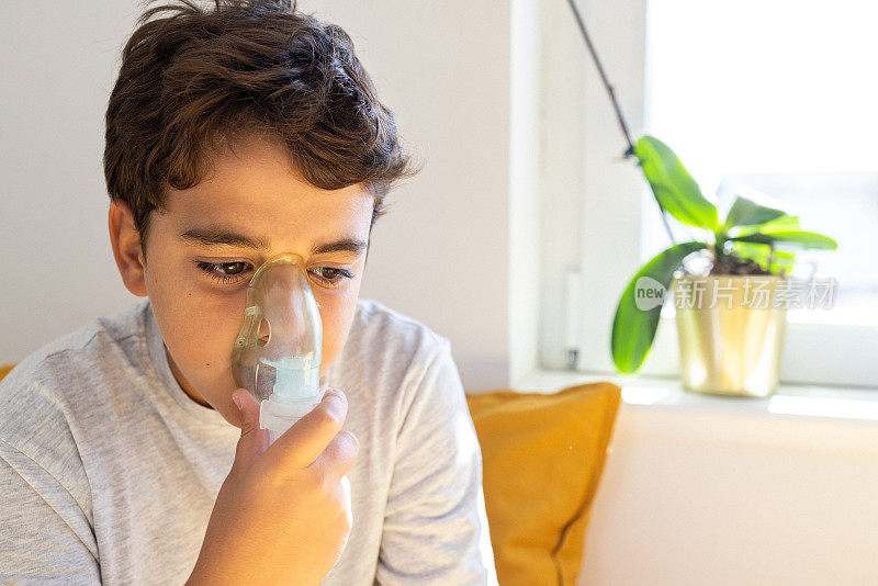 患有哮喘的高加索男孩在家里使用雾化器，帮助他更好地呼吸