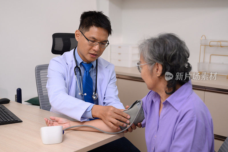 男医生在检查室测量一位老年女病人的血压。