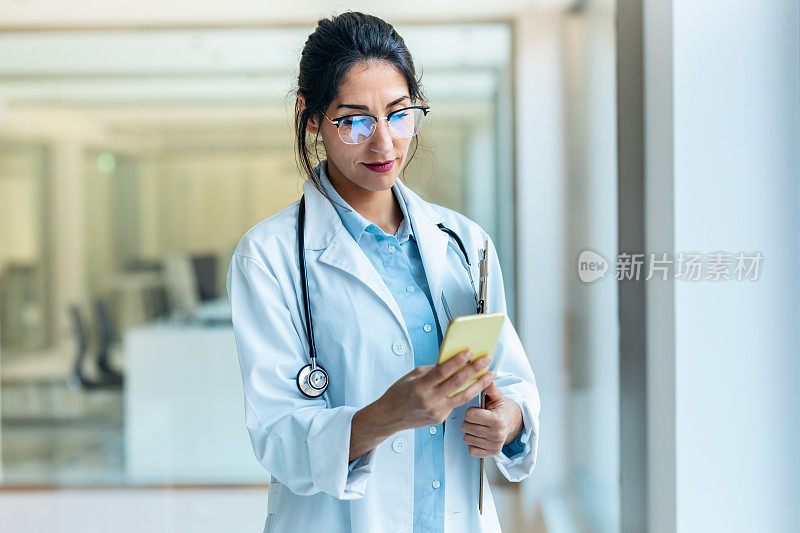 美丽的女医生站在医疗咨询时使用智能手机。