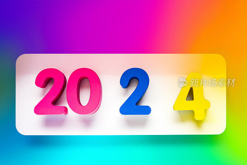 在美丽的多色渐变背景上，彩色木块字母传达了即将到来的2024年新年的含义。