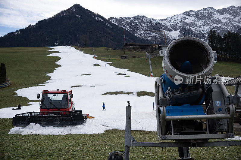 在奥地利蒂罗尔沃尔什的滑雪场，雪车(雪猫，雪道机或雪道修护机)和雪炮正在等待被用来准备滑雪道。背景中的滑雪缆车(t型缆车)。