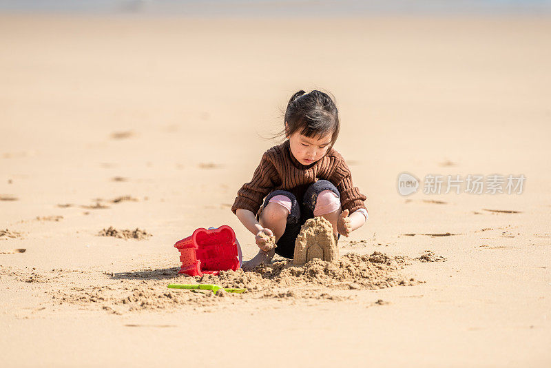 一个中国小女孩在沙滩上玩沙子