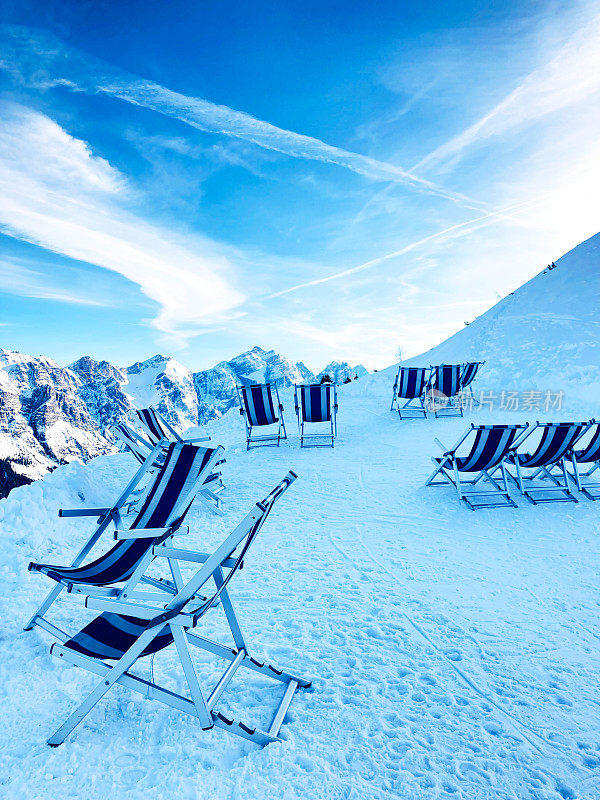 迷人的白雪皑皑的阿尔卑斯山和甲板上的椅子在梦幻般的蓝天