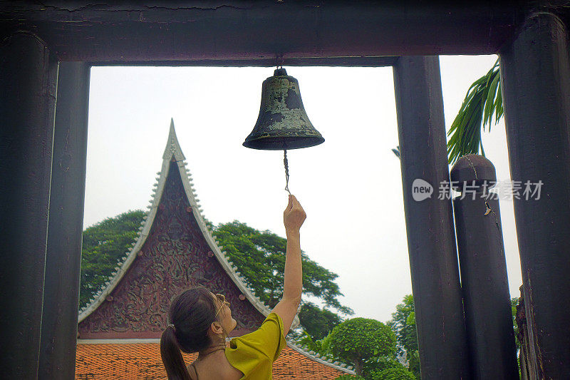 年轻女子在寺庙里摇佛钟