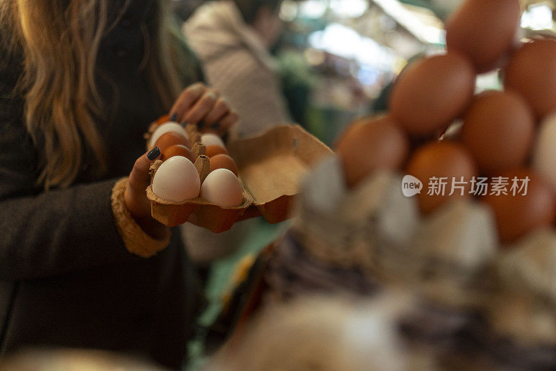 一个面目全非的女人在街头市场买鸡蛋，特写是她手拿纸板箱