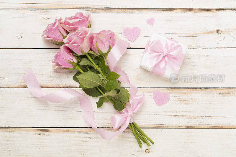 粉红色玫瑰与心和礼盒木制背景，俯视图。