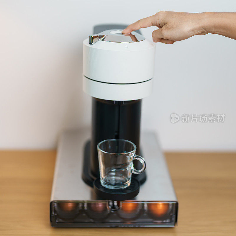 用咖啡机手工制作意式浓缩咖啡，并在木桌上放置烘焙好的咖啡豆胶囊。每日饮品饮品适用于家庭、公寓和办公室的概念