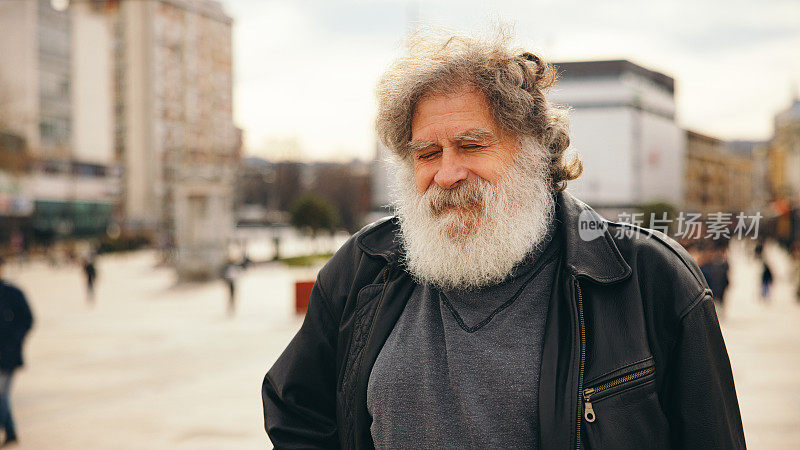 一个年长的白人男子的肖像，在城市里，有一头长长的白发和胡子