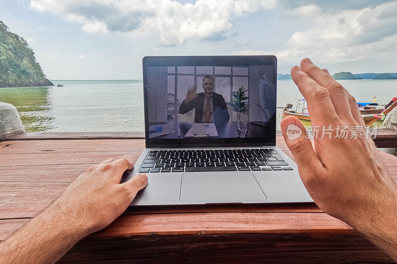 在泰国的一个海滩酒吧里，一个年轻人正在和他的同事进行视频通话