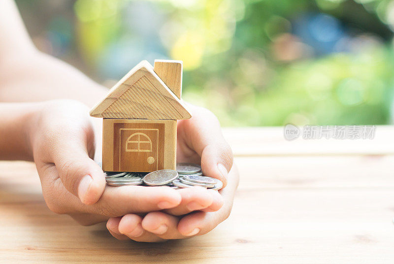 硬币和家居模型放在手上是计划省钱的硬币买一个住宅概念概念的房产梯子，