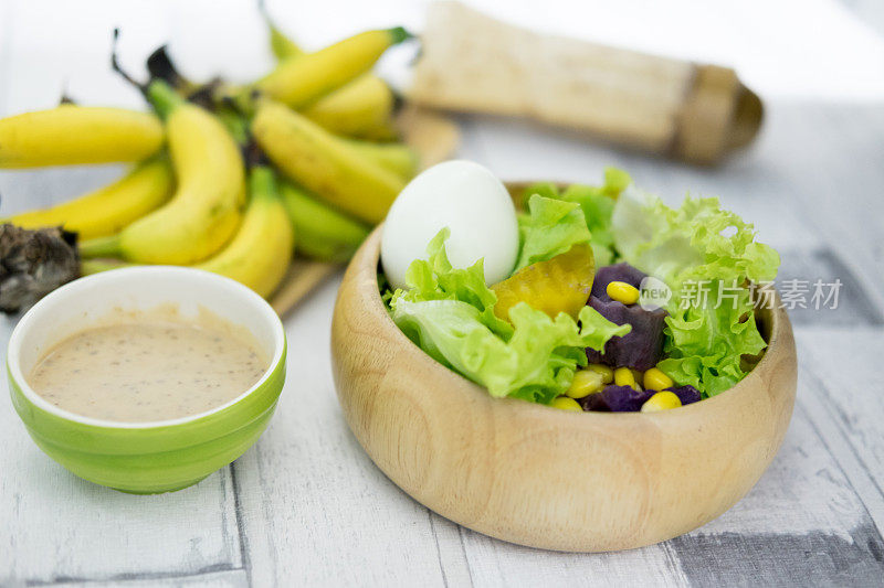 新鲜水果和蔬菜沙拉(生菜，南瓜，玉米，山药和煮鸡蛋)与奶油沙拉在木碗。健康食品的概念