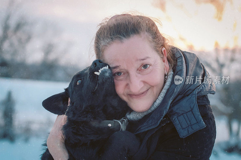 年长妇女有乐趣与狗在冬天的一天