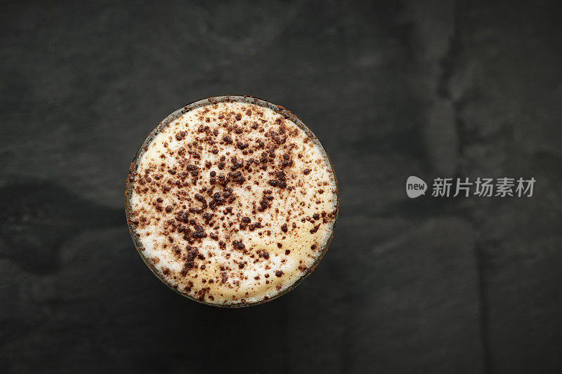 卡布奇诺与巧克力洒在一个杯子，在深色石板的背景。