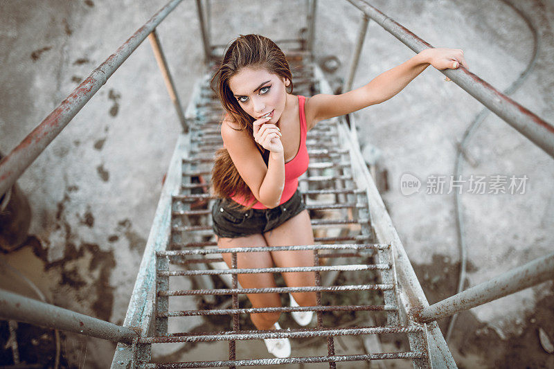 高角度的可爱的女性摆姿势在生锈的金属楼梯