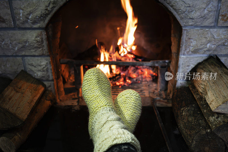 脚上穿着羊毛袜子，在壁炉旁暖着