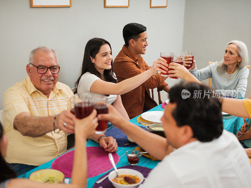 美丽的墨西哥家庭坐在餐桌前互相敬酒