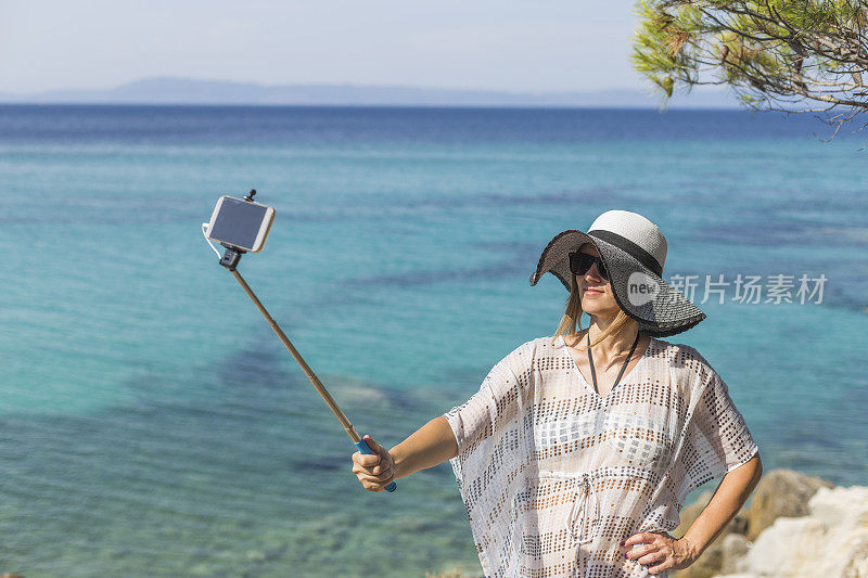 美丽的女人用手机相机自拍。