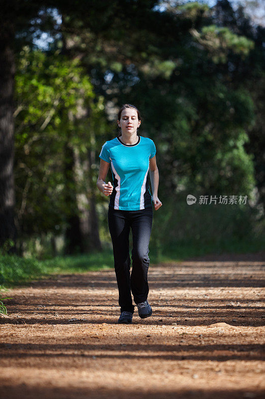 美丽的年轻女子在森林里奔跑以保持健康