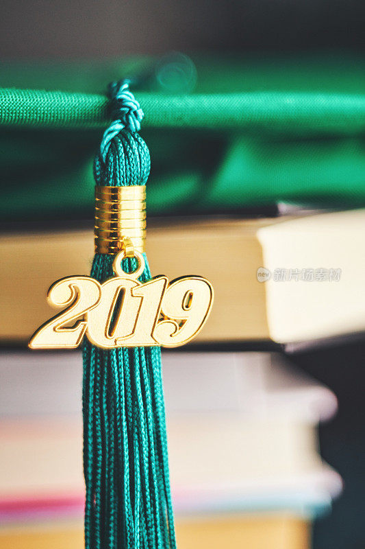 带2019年毕业流苏和书籍的绿色学士帽