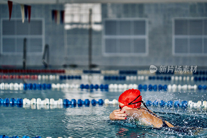 女运动员蝶泳式游泳。水花四溅向不同的方向。