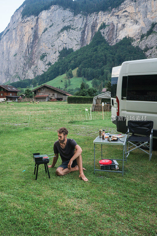 在瑞士阿尔卑斯山露营的男人正在烤汉堡